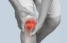 Person holding an inflamed knee joint highlighted in red, indicating joint pain or arthritis symptoms