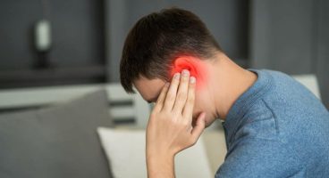 Man holding his ear in pain with red inflammation highlight, indicating an ear infection or earache