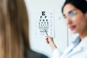 Female optician pointing at a Snellen eye chart during an eye exam in an ophthalmology clinic